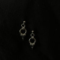 a pair of silver earrings on a black surface