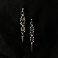 a pair of silver spike earrings on a black background