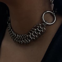 a close up of a woman wearing a chain choker