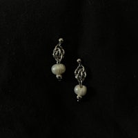 a pair of silver earrings on a black surface